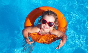 petite fille dans une piscine avec une bouée orange