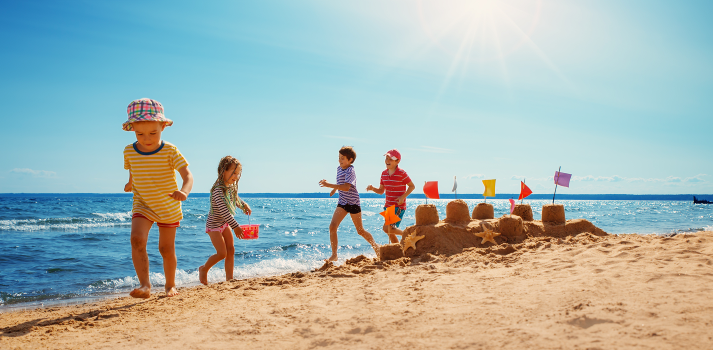 enfants en vacances qui jouent sur une plage et font un château de sable